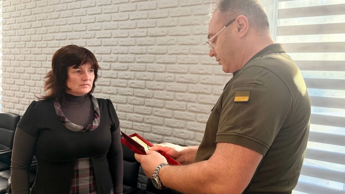 Військовий вручає червону скриньку з орденом жінці в кабінеті