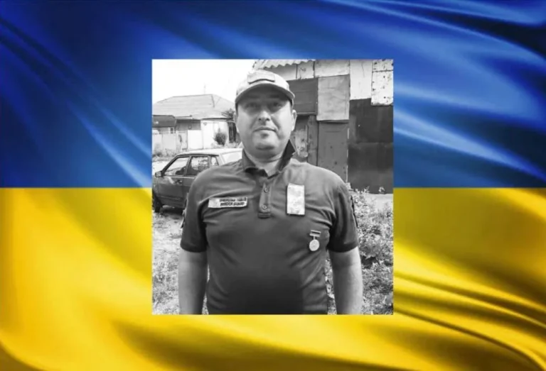 Чорно-білий портрет прикордонника в кепці та поло з медаллю на тлі прапора України
