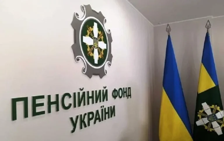 Емблема та вивіска Пенсійного фонду України на стіні біля прапорів