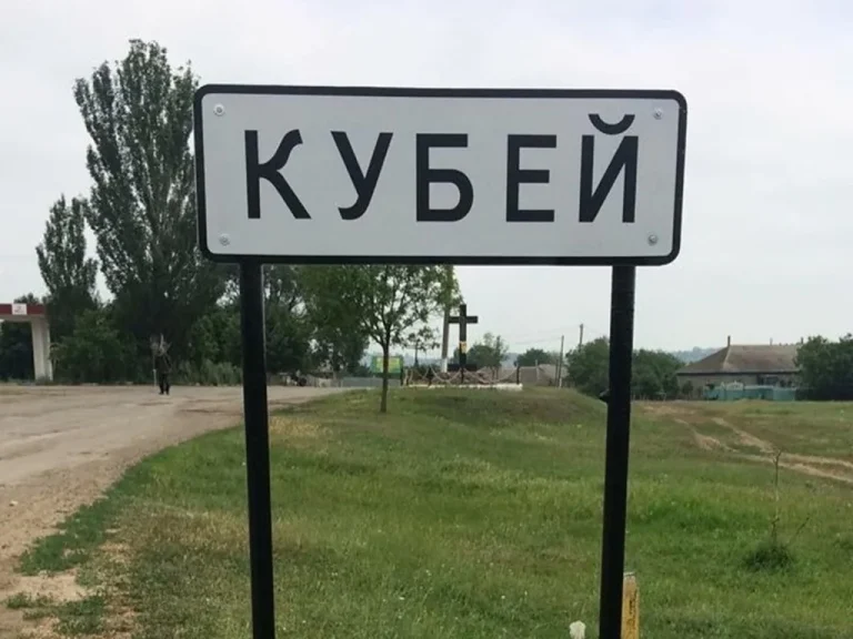 Дорожній знак Кубей біля ґрунтової дороги серед зеленої сільської місцевості