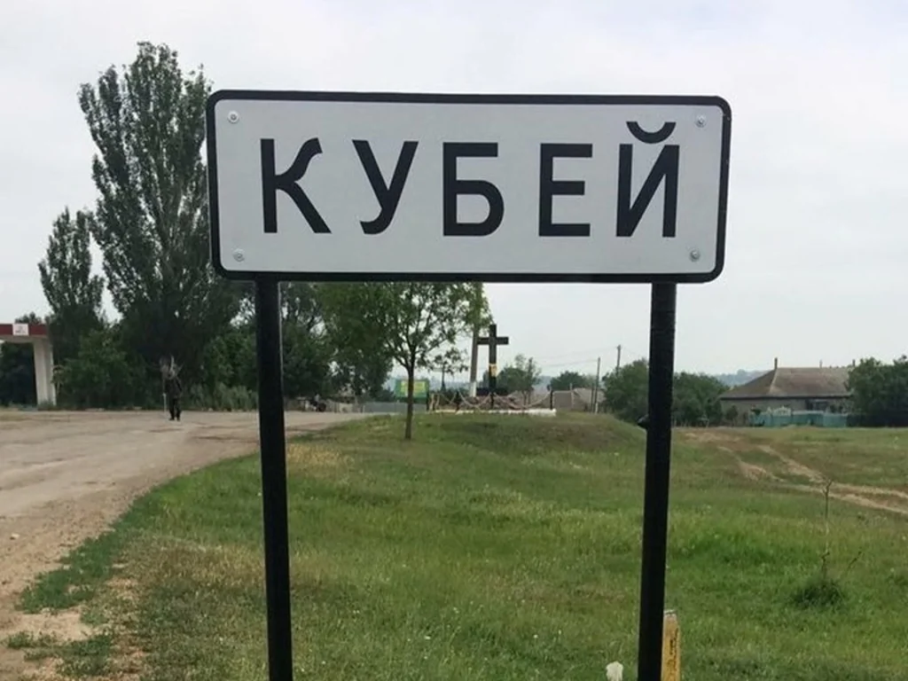 Дорожній знак Кубей біля ґрунтової дороги серед зеленої сільської місцевості